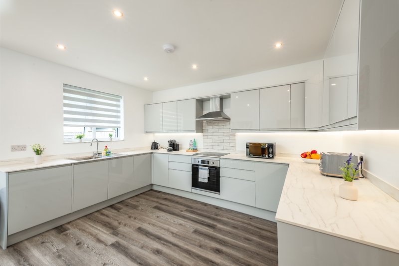 Modern kitchen with white cabinetry, stainless steel appliances, white subway tile backsplash, and wood-effect flooring