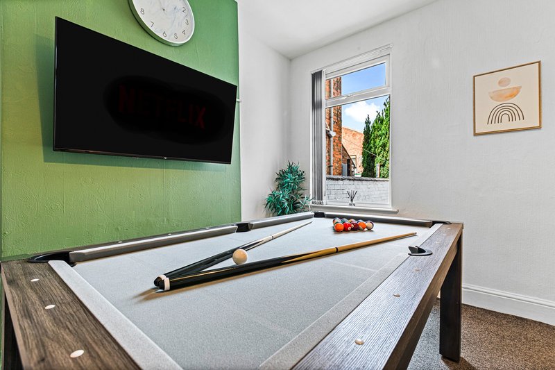 Recreation room with pool table, wall-mounted TV, window with garden view, and minimalist wall art