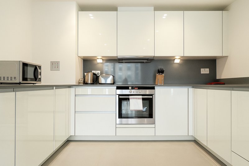 Modern kitchen with white cabinetry, built-in oven, stovetop, and stainless steel appliances