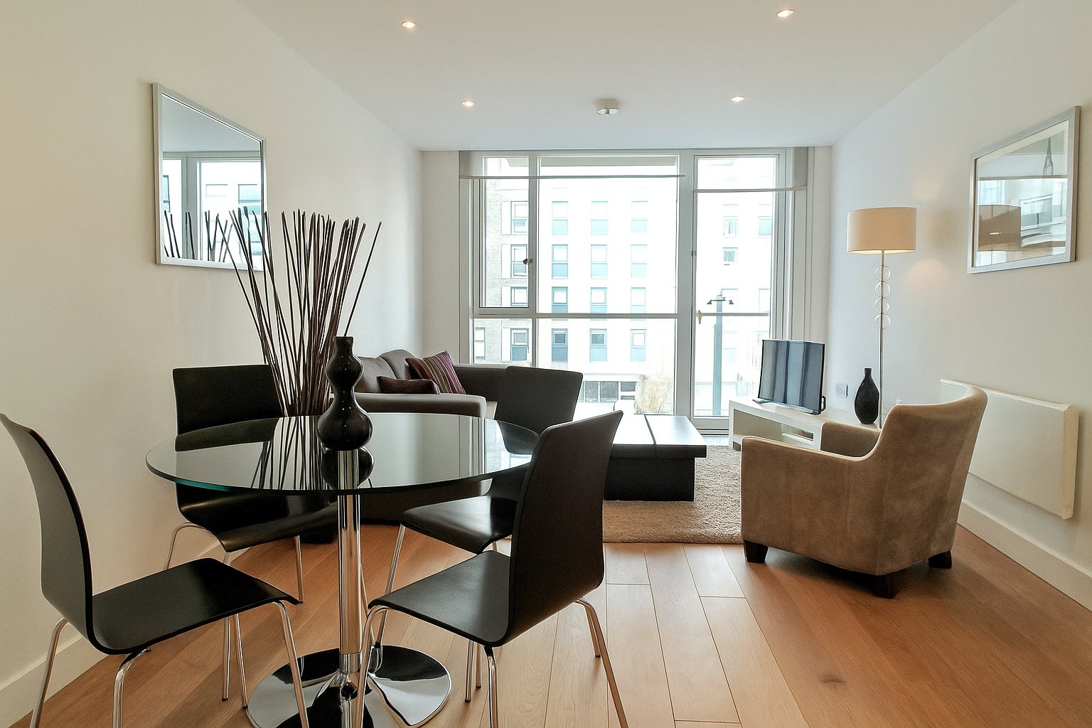 Modern apartment interior with dining table, chairs, sofa and city views from large windows