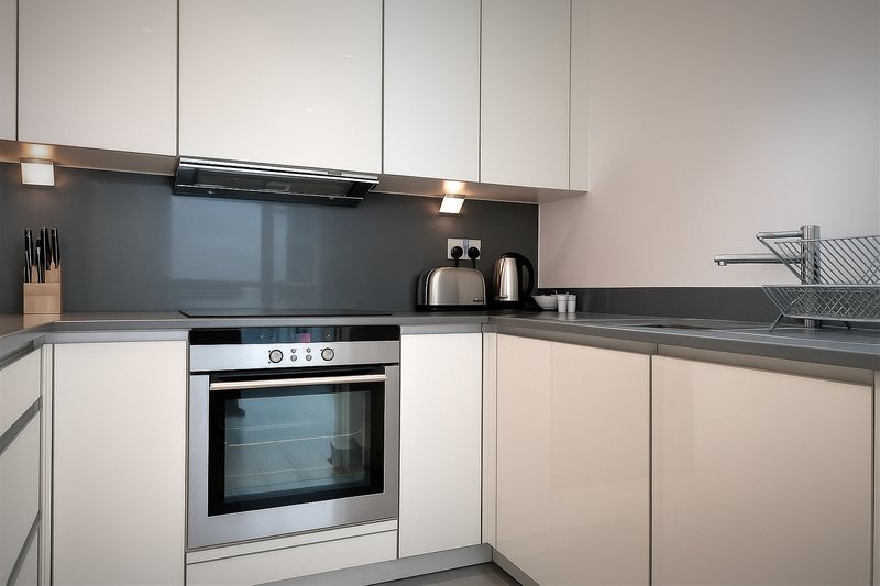 Modern kitchen with white cabinetry, grey countertop, built-in oven and hob