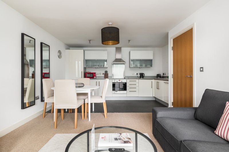 Open-plan living space with dining table, kitchen, sofa and full-length mirror