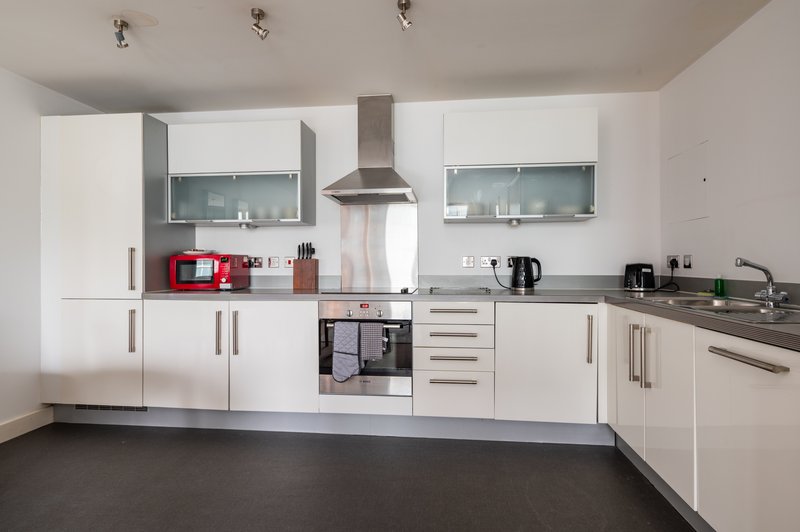 Modern kitchen with white cabinets, stainless steel appliances, and dark flooring