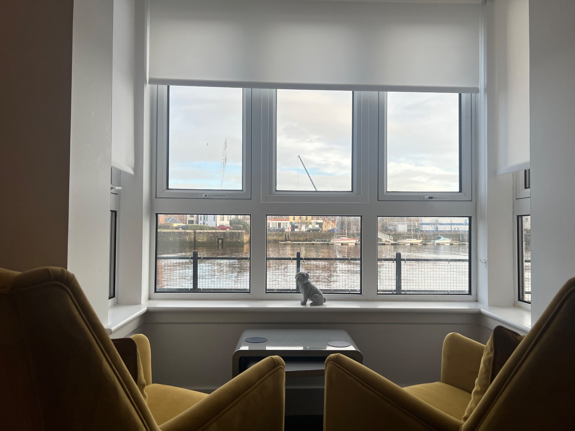 Modern sitting area with two mustard armchairs facing large bay windows overlooking cityscape
