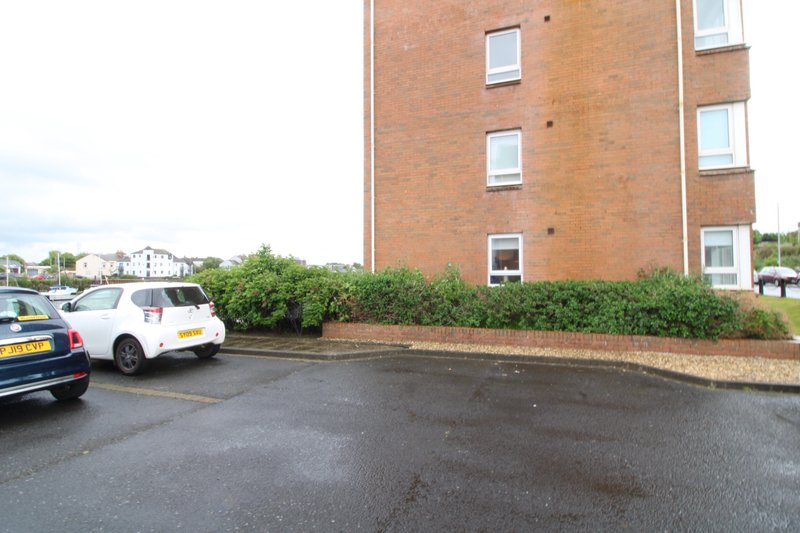 Brick apartment building exterior with parking area and parked cars