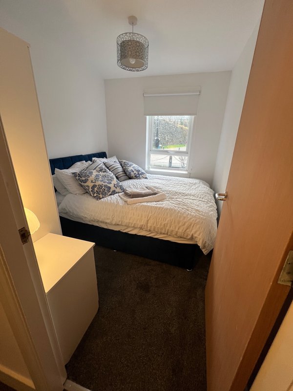 Small bedroom with double bed, patterned cushions, pendant light and window view