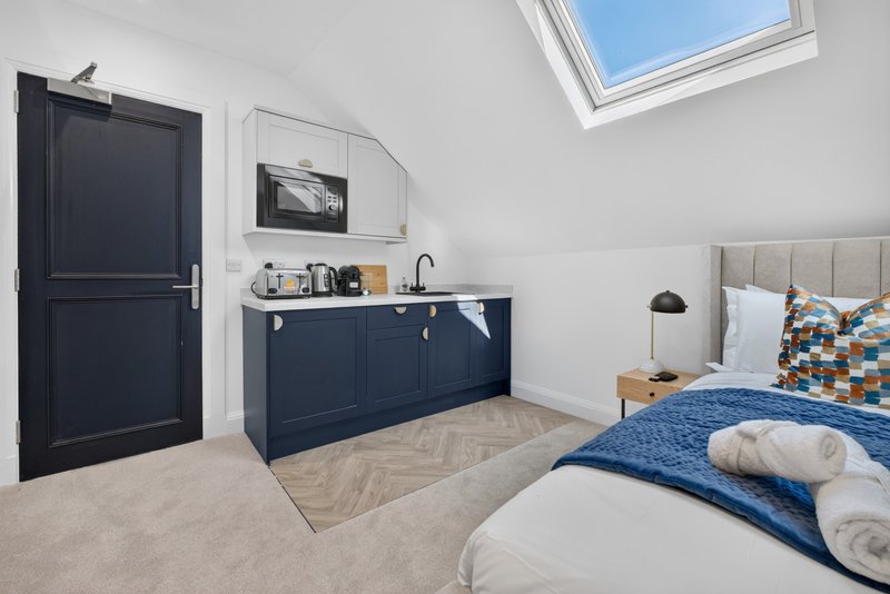Modern bedroom with double bed, navy kitchenette, skylight and rolled towels