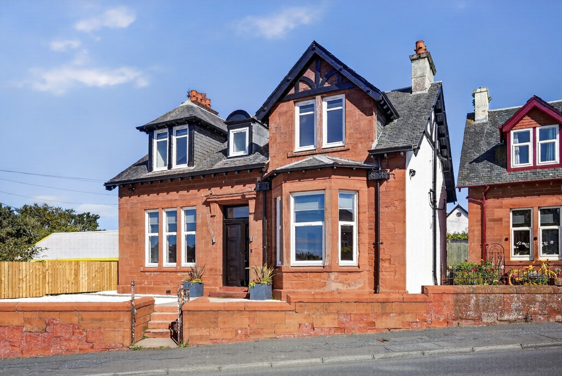 Red brick Victorian villa with bay windows, mansard roof and front garden boundary wall