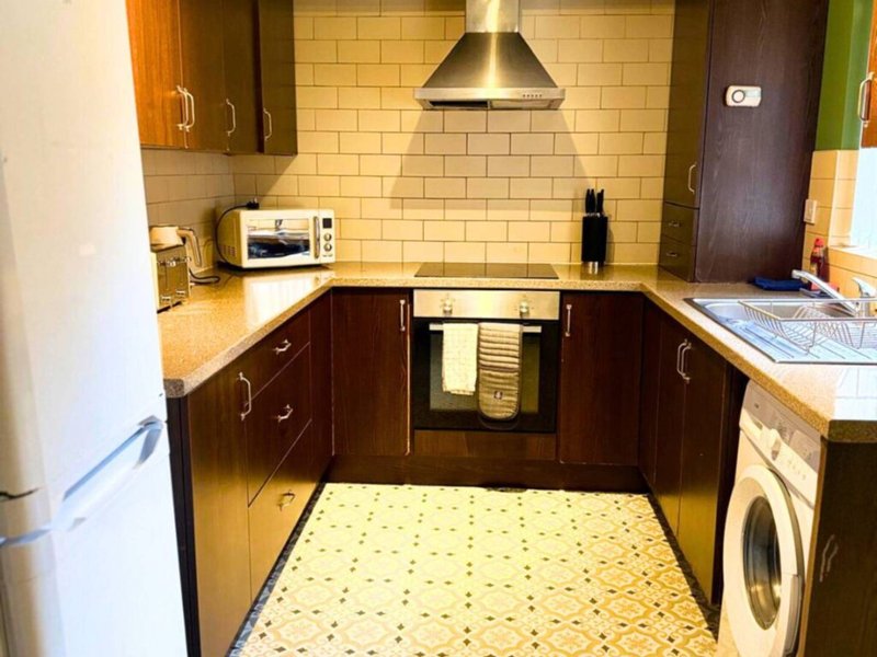 Modern kitchen with dark cabinets, yellow subway tile backsplash, stainless steel appliances and extractor hood