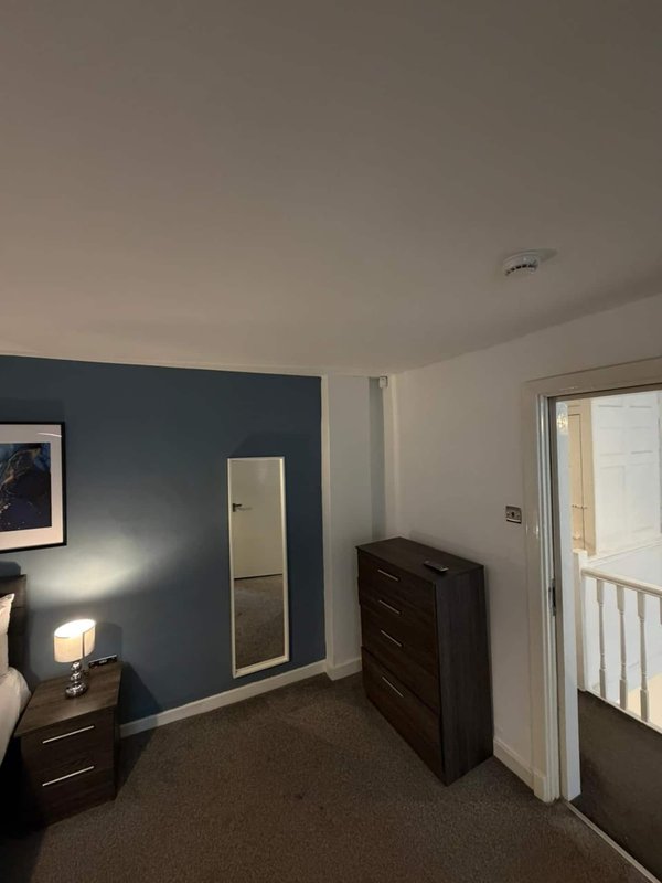 Bedroom with dark blue accent wall, dark wood furniture, bedside lamp, and white door to balcony