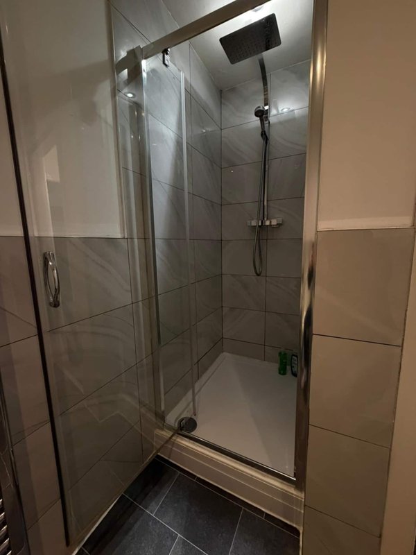 Modern bathroom with walk-in shower enclosure, tiled walls and black floor