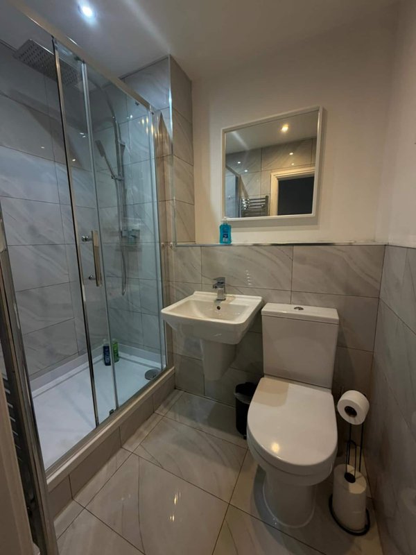 Modern bathroom with shower cubicle, toilet, sink and illuminated mirror