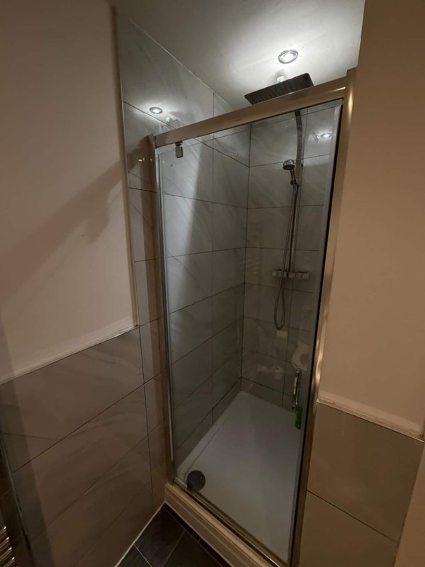 Modern bathroom with glass shower enclosure, tiled walls, and recessed lighting