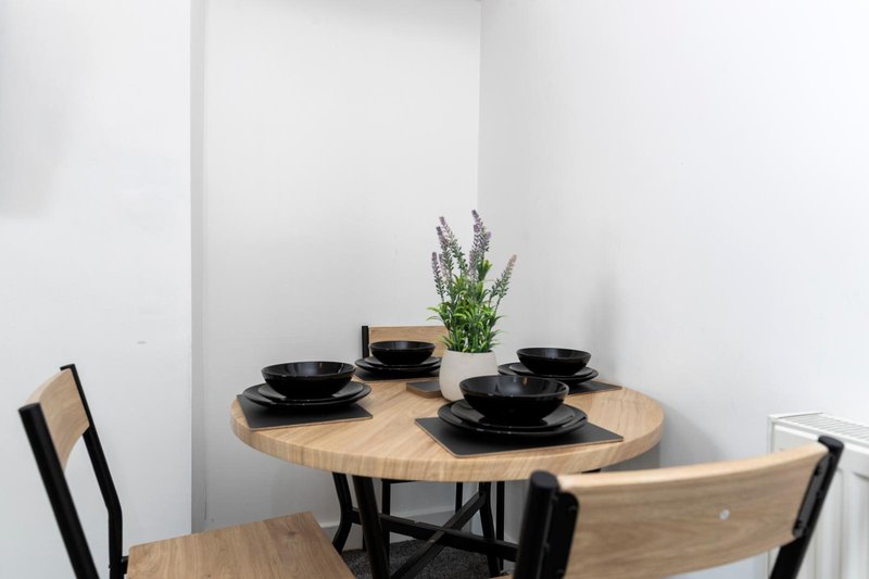 Dining table set with black plates, wooden chairs, and potted plant centerpiece