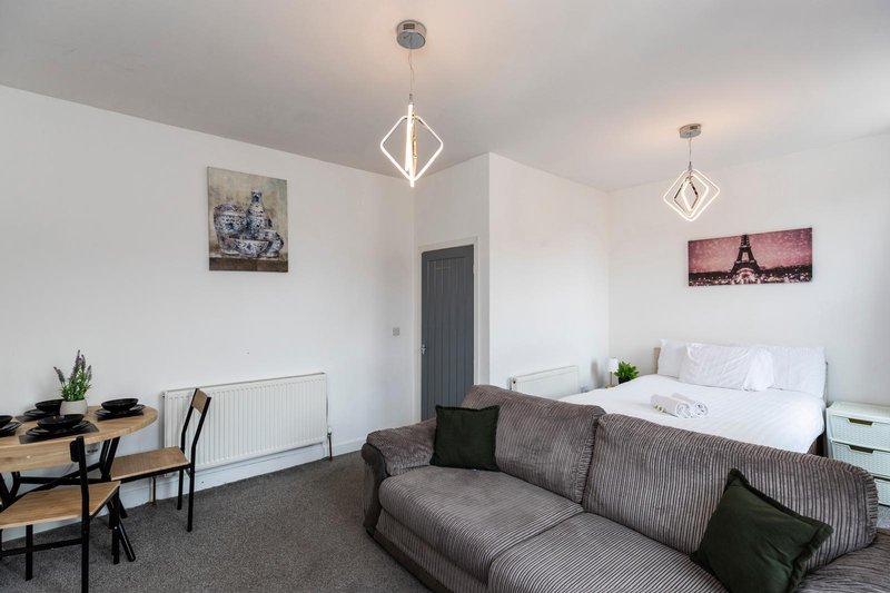 Bright bedroom with double bed, sofa, desk, pendant lights and wall art
