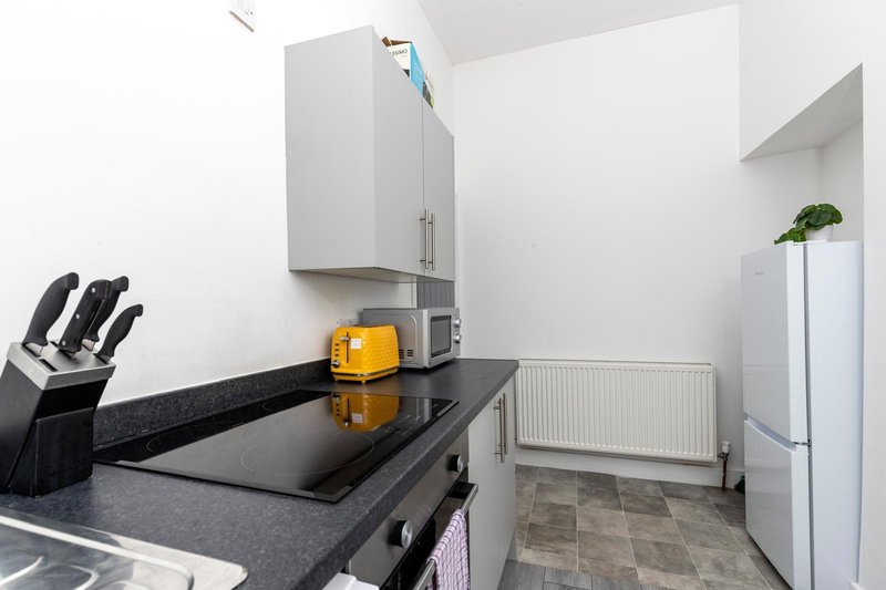 Modern kitchen with black countertop, white cabinets, stainless steel appliances and knife block