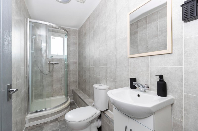 Modern bathroom with shower cubicle, toilet, white sink and mirror