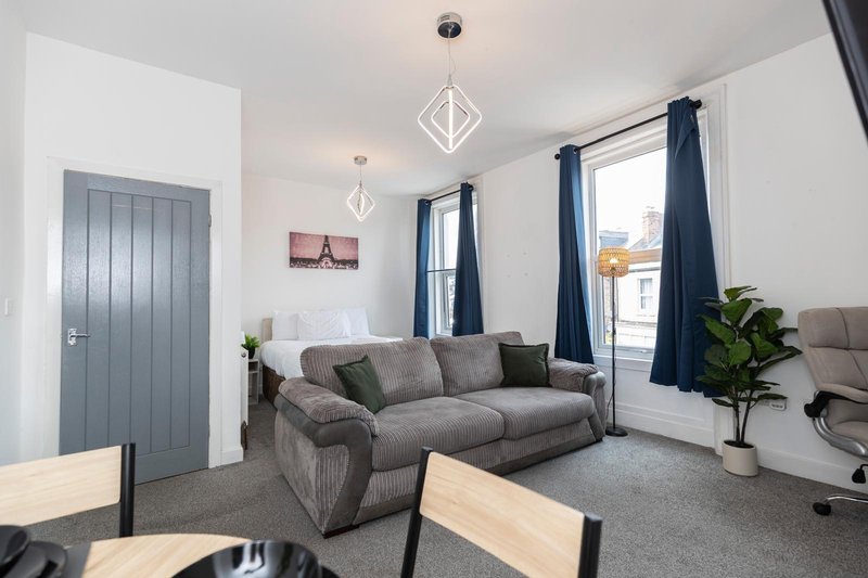 Modern living room with grey corner sofa, dining table, blue curtains and pendant lights