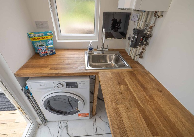 Compact kitchen with washing machine, sink, wooden countertop and window