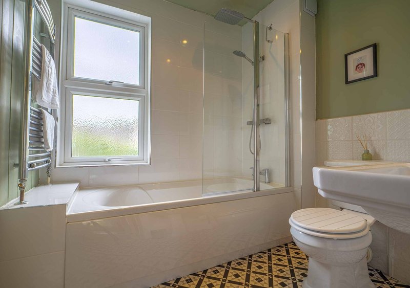 Modern bathroom with bathtub, glass shower enclosure, toilet, sink and window
