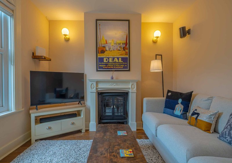 Modern living room with cream sofa, fireplace, TV stand, wall sconces and framed artwork