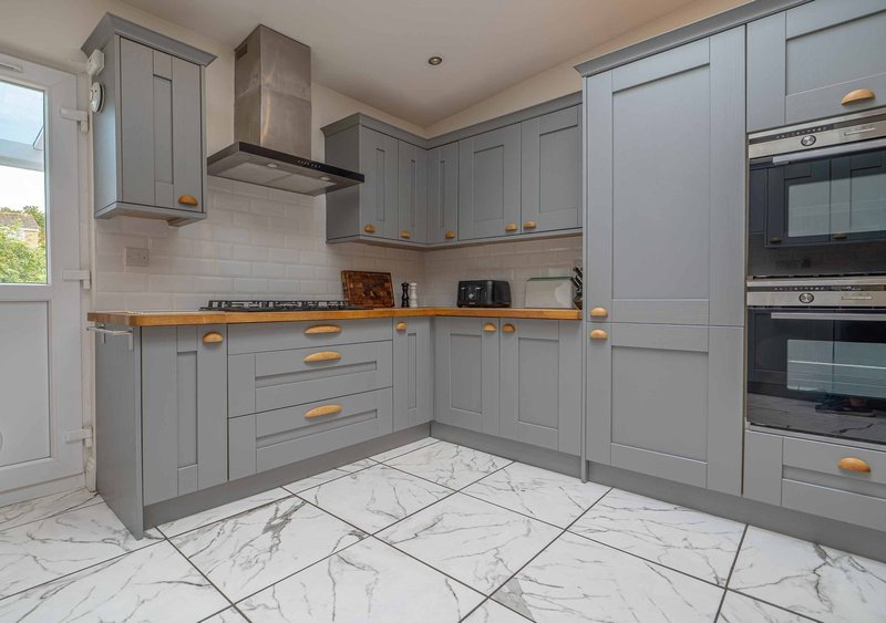 Modern kitchen with grey cabinetry, marble flooring, stainless steel appliances and wooden worktops