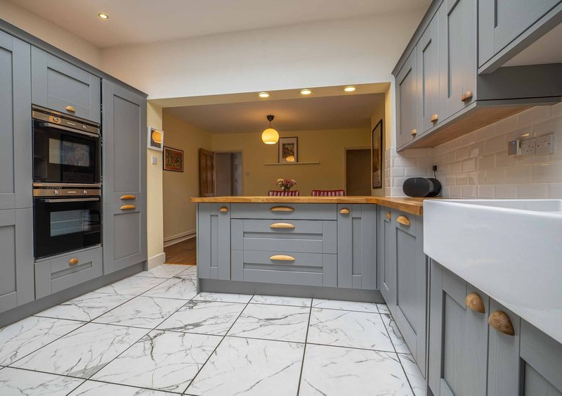 Modern kitchen with grey cabinetry, marble floor, island counter and integrated appliances