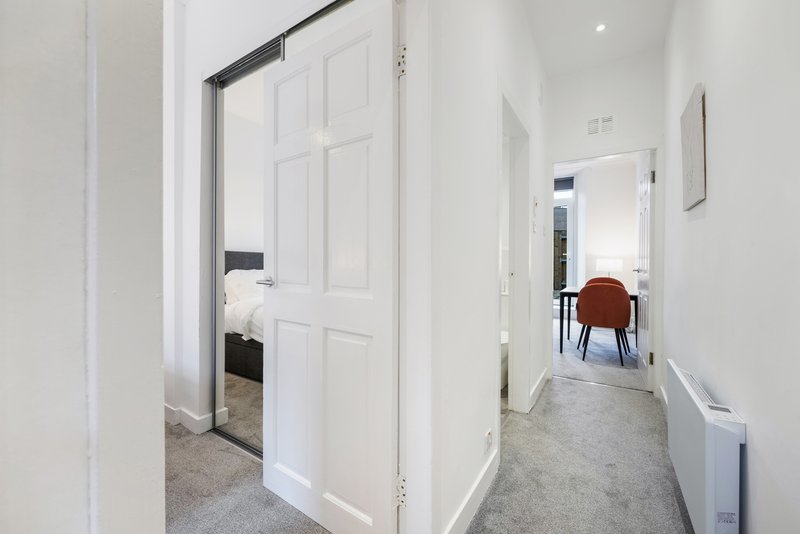 Bright hallway with white panelled doors, grey carpet, and modern minimalist interior