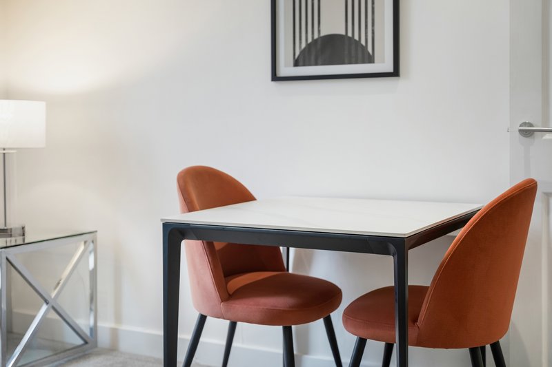 Modern dining area with black table and two rust-colored velvet chairs