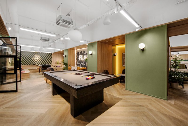 Modern games room with pool table, wooden flooring, green accent wall and lighting