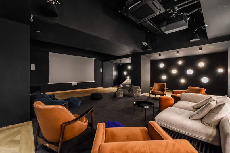 Modern media room with projection screen, orange chairs, bed seating, and ambient lighting