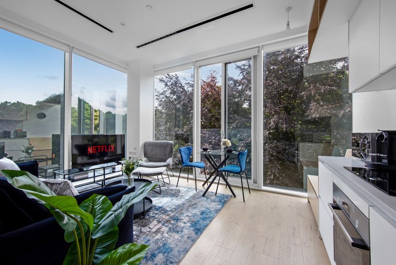 Open-plan living space with kitchen, dining area, fireplace and garden views through large windows