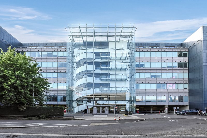 Modern glass and steel building complex with curved central structure and multiple residential floors