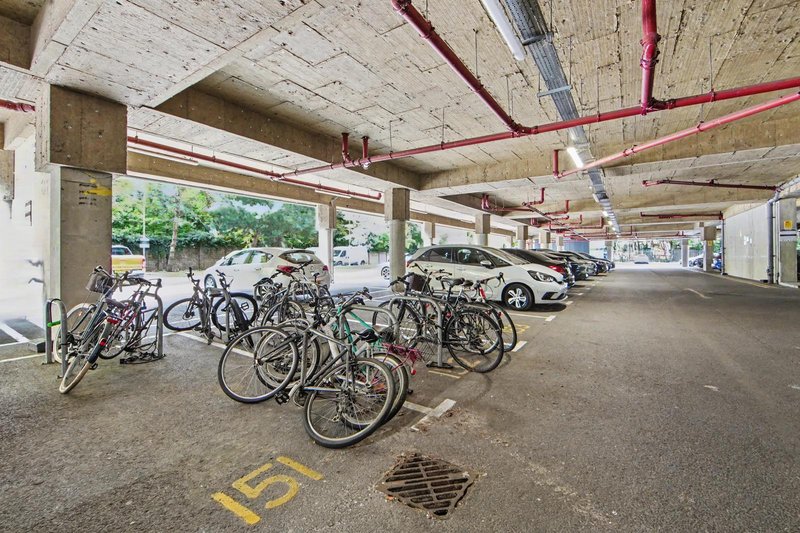 Underground parking garage with bicycles parked and cars visible in background