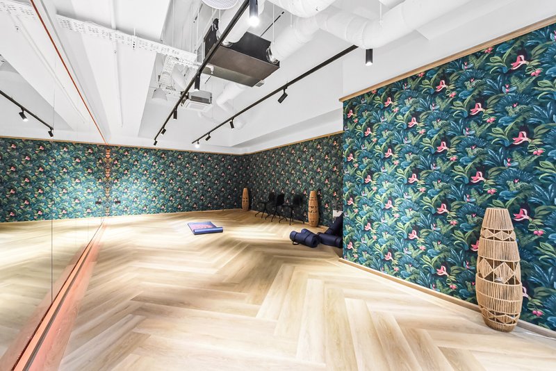 Spacious studio room with herringbone wood flooring, teal patterned wallpaper, and professional lighting setup