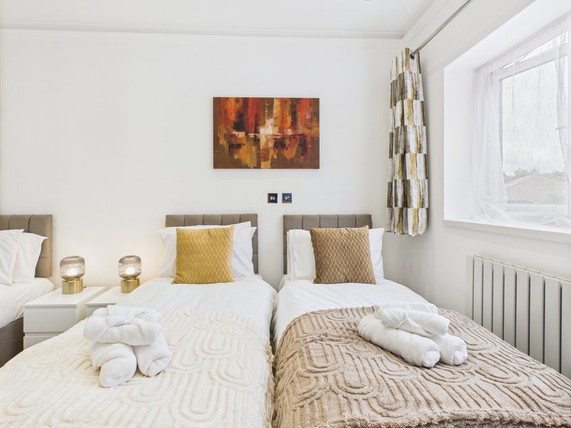 Twin bedroom with two single beds, patterned bedding, yellow cushions and abstract wall art