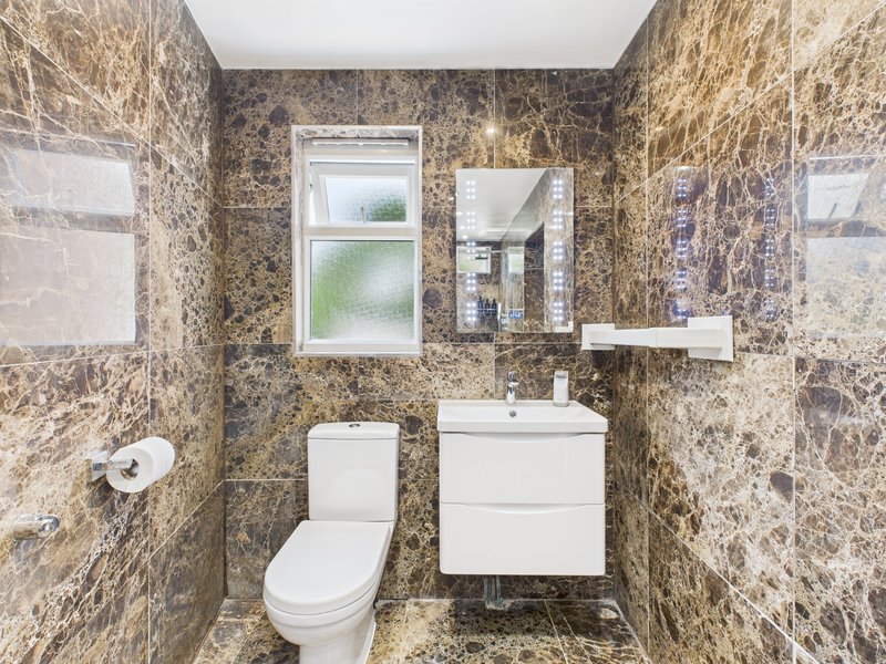 Modern bathroom with granite tiles, white sink vanity, toilet, and mirror