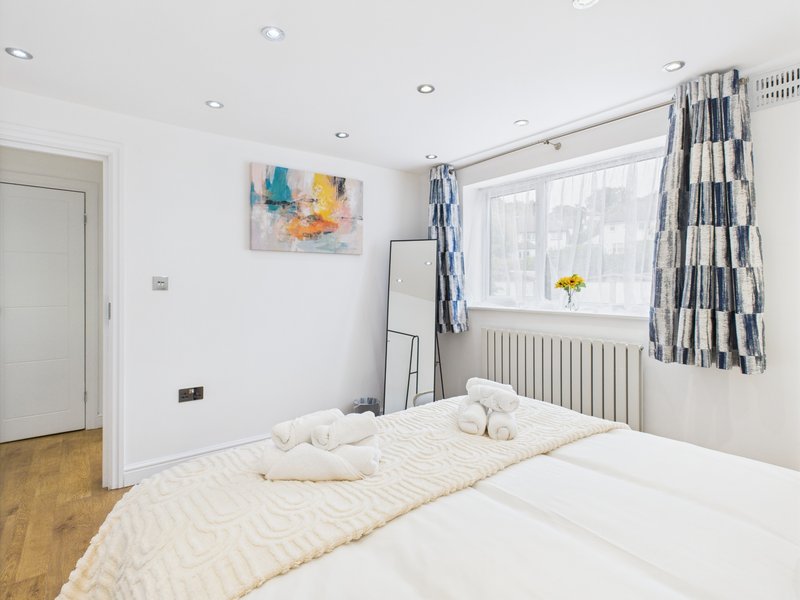 Bright modern bedroom with double bed, large window, striped curtains and abstract wall art