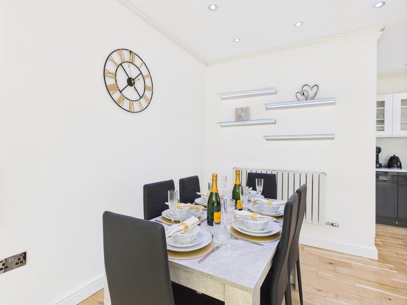 Modern dining room with marble table, black chairs, wine bottles and place settings