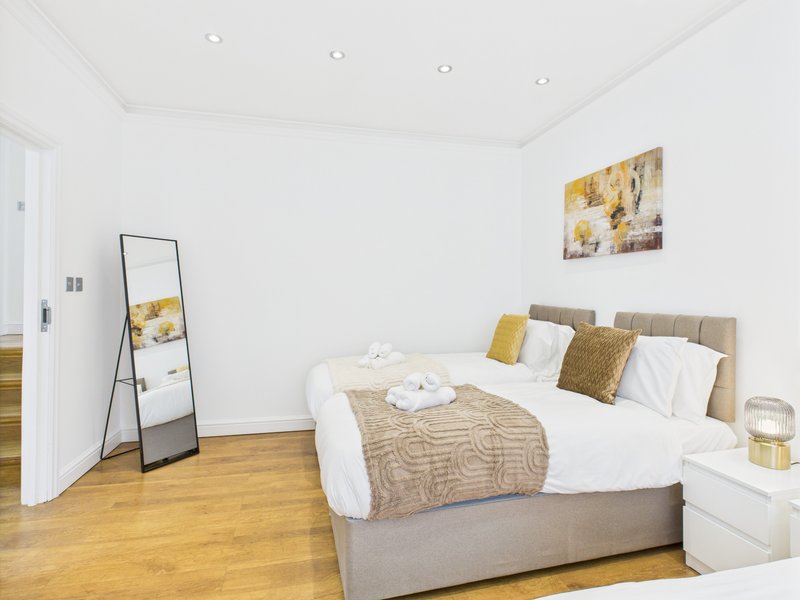 Modern bedroom with double bed, wooden floor, white walls and gold accents