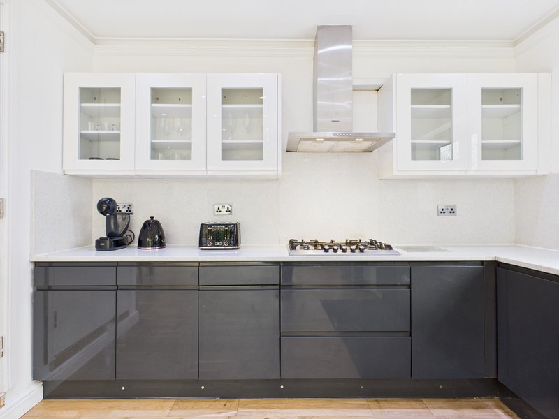 Modern kitchen with white upper cabinets, dark lower cabinets, stainless steel range hood and wooden flooring