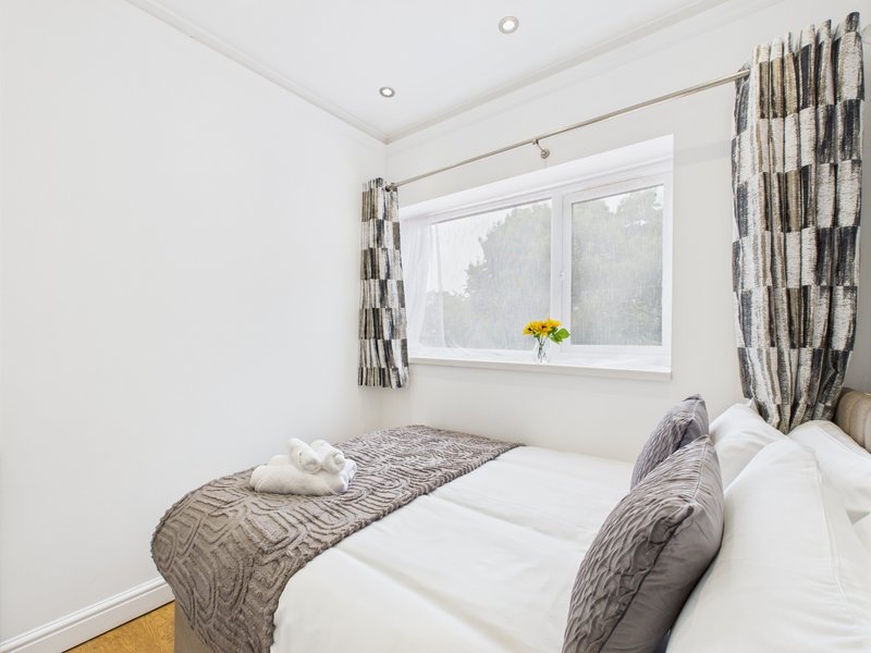 Bright bedroom with single bed, patterned bedding, gray curtains and window with yellow flowers
