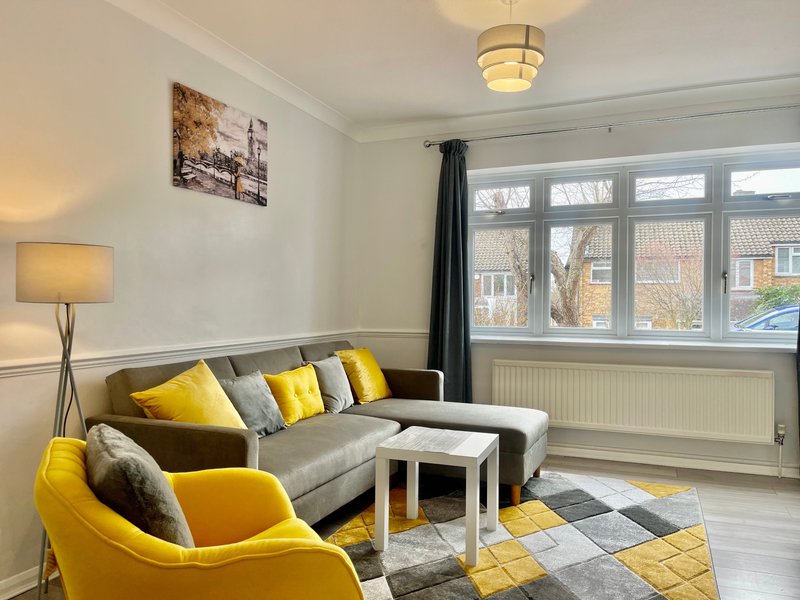 Modern living room with gray sofa, yellow armchair, geometric rug and large windows