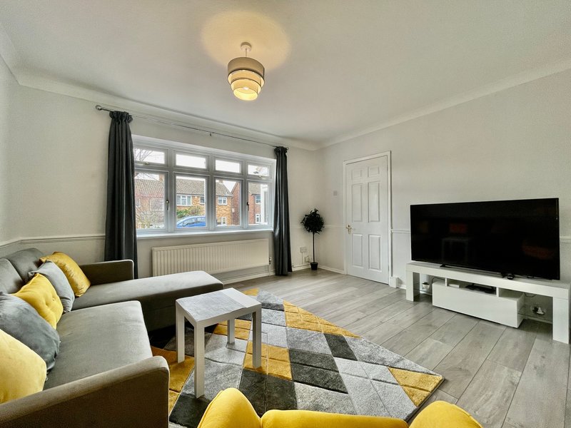 Modern living room with grey sofa, yellow cushions, TV, and large window