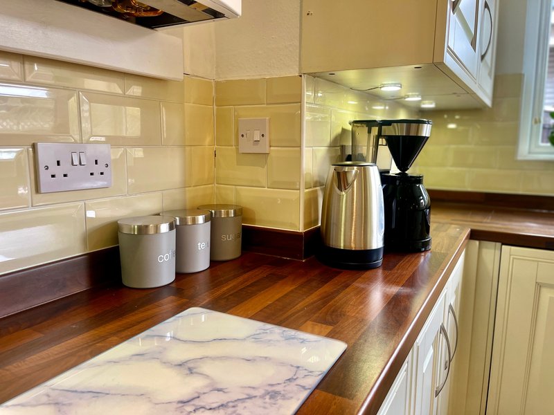 Kitchen countertop with kettle, coffee maker, storage containers and marble chopping board