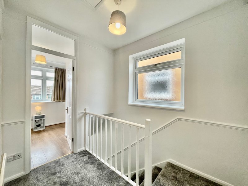 Landing area with white stair rail, pendant light, and doorway to adjoining room