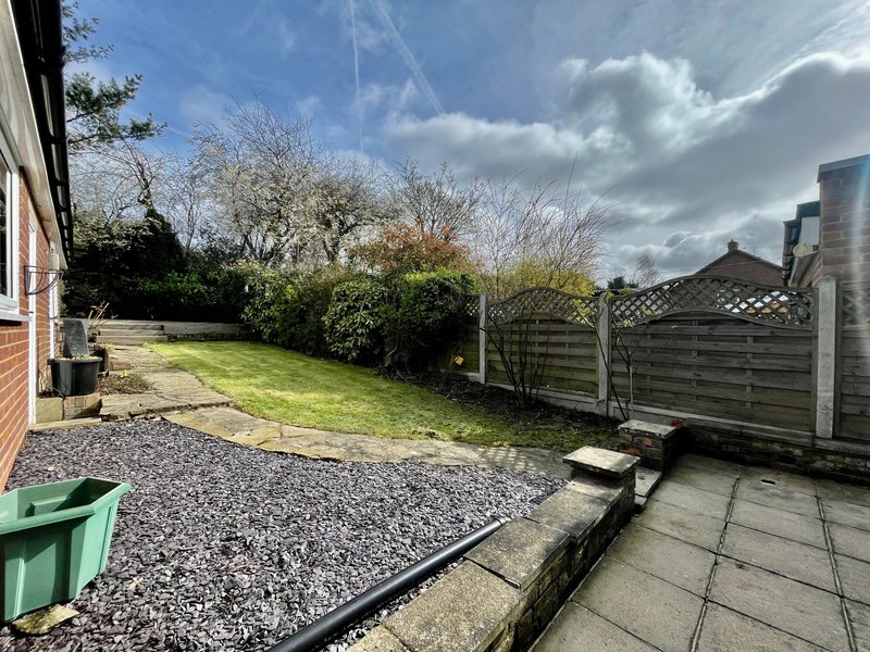 Rear garden with gravel area, lawn, wooden fence, and patio paving