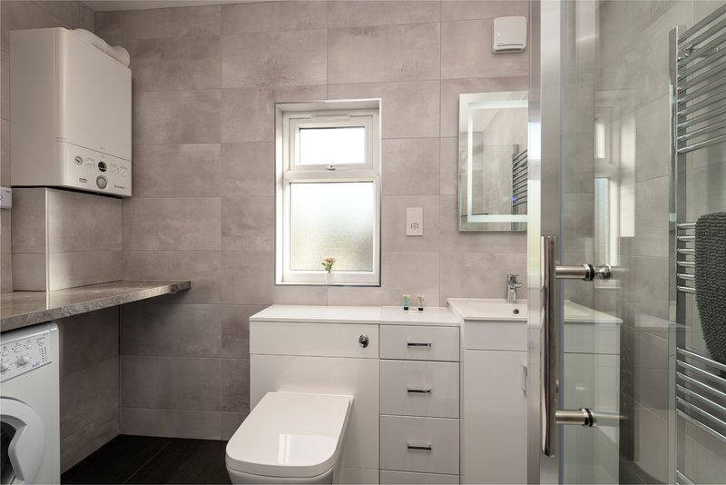 Modern bathroom with toilet, vanity sink, shower enclosure and heated towel rail