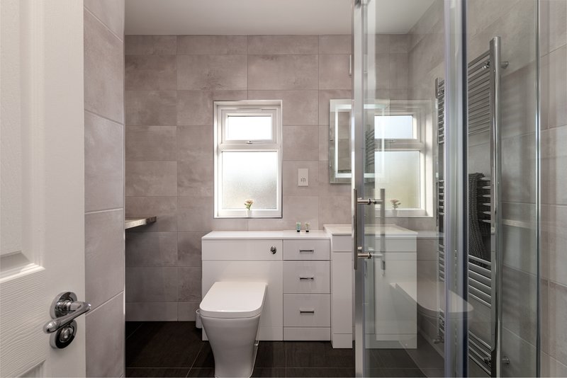 Modern bathroom with white vanity, toilet, walk-in shower and heated towel rail