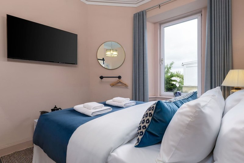 Modern bedroom with twin beds, blue bedding, wall-mounted TV and circular mirror